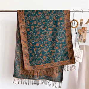 Detail of teal and bronze paisley scarf with elegant tassels and soft texture.