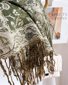 Close-up of elegant green paisley scarf with intricate fringe detail and woven texture