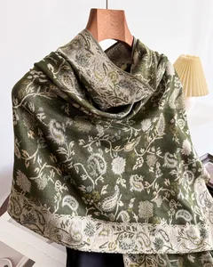 Detailed close-up showing the intricate dark green paisley floral jacquard pattern on a winter shawl