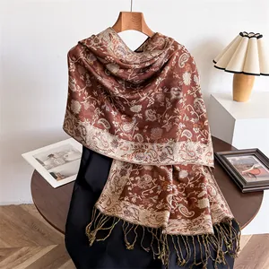 Detailed view of elegant paisley pattern scarf with fringes in warm rust brown.
