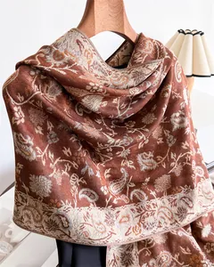 Detail view of an elegant paisley patterned winter scarf in warm terracotta tones.