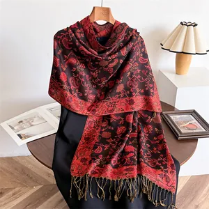 Detailed macro view of an elegant red paisley winter shawl featuring tassels and patterns