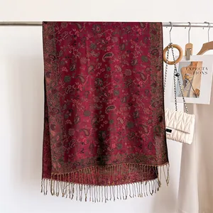 Detailed view of an elegant burgundy paisley shawl with tassels and fashion props
