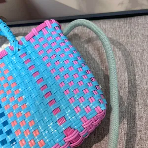 Detailopname van kleurrijke blauw en roze gevlochten emmer tas met touw handvat