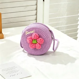 Macro view of purple woven straw bag for girls featuring a pink crochet flower accent