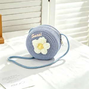 Close-up of a blue woven straw bag for girls featuring a big white crochet flower