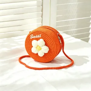 Detail view of girls' orange woven straw crossbody bag with white flower decoration