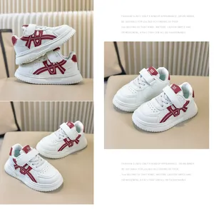 Dettaglio ravvicinato di sneaker bianche per bambini con accenti rossi e velcro.