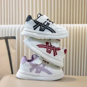 Una pila di scarpe sportive bianche per bambini nei colori nero, rosso e viola chiaro
