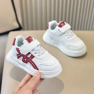 Primo piano di scarpe sportive bianche per bambini con accenti bordeaux e suola morbida