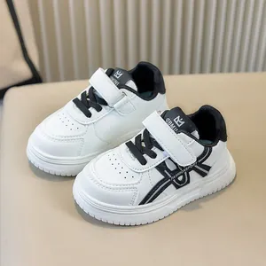 Dettaglio di scarpe sportive bianche per bambini con accenti neri e chiusura a strappo