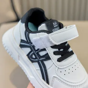 Primo piano di sneakers bianche per bambini con velcro e logo sulla linguetta.