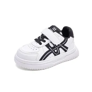 Dettaglio laterale di scarpe sportive bianche per bambini con accenti neri e velcro