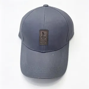 Vista dettagliata di un cappellino da baseball grigio con toppa in pelle EDIKO sul davanti