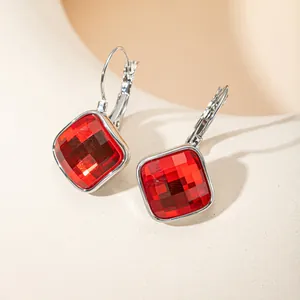 Gros plan détaillé des boucles d'oreilles en cristal rouge de forme carrée et polie
