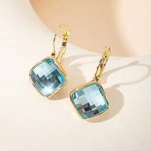Détail de boucles d'oreilles carrées plaquées or 14K avec pierres de zircon bleu ciel.