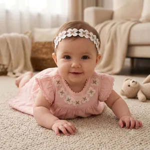 Bebé adorable con una elegante diadema de encaje floral dorado en una habitación suave