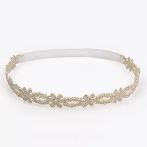 Vista detallada de una diadema de encaje floral dorado para bebé con banda elástica.