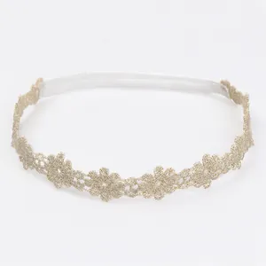 Primer plano de una diadema de encaje floral dorado para bebés con banda elástica blanca