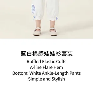 Detail view of girls' white cropped pants with blue ribbon accents and scalloped shoes