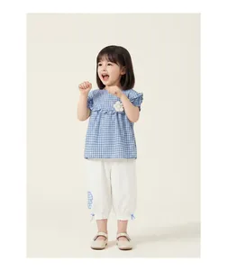 Toddler girl modeling a blue gingham doll shirt and white capri pants summer set