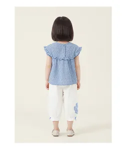 Back view of girl's summer outfit featuring blue checkered ruffle top and white floral pants