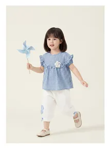 Cute toddler girl summer outfit featuring blue plaid doll blouse and white leisure pants