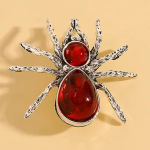 Dettaglio macro di una spilla a ragno in argento vintage con pietre rosse trasparenti