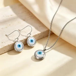 Detail van Evil Eye sieradenset met schelphanger en oorbellen op zijden achtergrond.