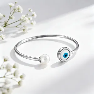 Dettaglio di un bracciale rigido aperto in acciaio al titanio con malocchio e perla