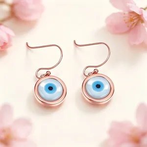 Primo piano dettagliato degli orecchini a gancio Evil Eye in oro rosa con smalto blu.