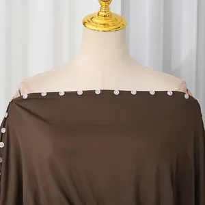 Dettaglio dei bottoni bianchi sul top marrone con spalle scoperte elegante