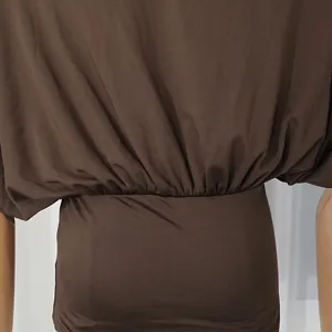 Dettaglio di top marrone con spalle scoperte e design a vita elastica aderente