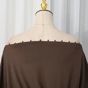 Dettaglio del top marrone con spalle scoperte e piccoli passanti sullo scollo