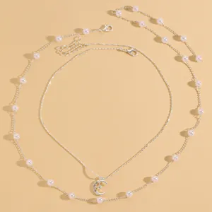 Dettaglio di una collana argentata a due strati con ciondolo a luna in zirconia.