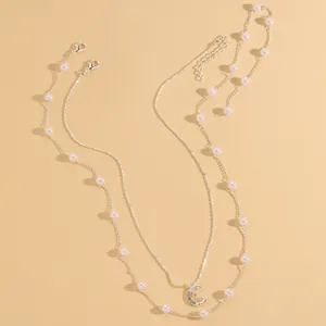Dettaglio collana a due strati con catena di perle e ciondolo a mezzaluna con zirconi