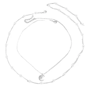 Dettaglio della collana a strati color argento con pendente a forma di luna e stella.