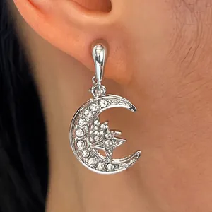Detailopname van elegante zilveren maan en ster druppeloorbel met micro-pave kristallen