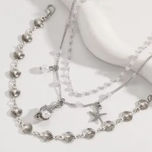 Primer plano de pulsera de tobillo de plata con dijes de concha y estrella de mar