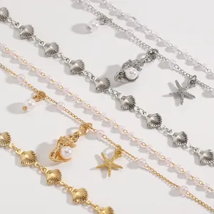 Primer plano de tobilleras playeras con dijes de concha marina, estrella de mar y perlas.