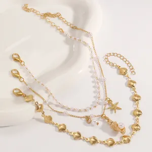 Conjunto de tobilleras doradas a capas con perlas y dijes náuticos de estrellas y conchas