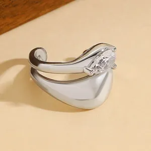 Close-up detail of silver ear cuff with water-drop cubic zirconia on warm background.