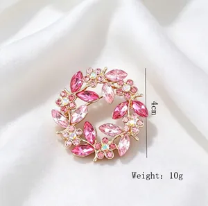 Detailed macro view of a vintage pink crystal floral wreath brooch on white satin fabric
