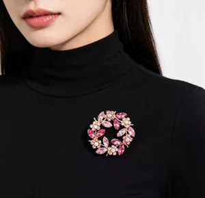 Close-up of a vintage pink crystal wreath brooch pinned on a black turtleneck sweater.
