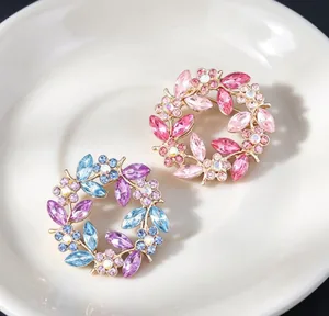 Detailed view of vintage crystal wreath brooches in pink and blue floral designs