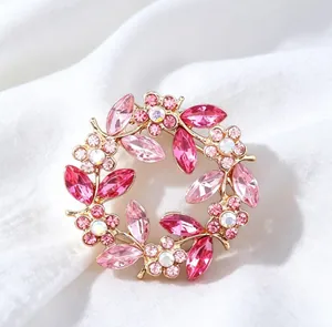 Macro view of a luxury vintage pink crystal wreath brooch set against soft white silk background