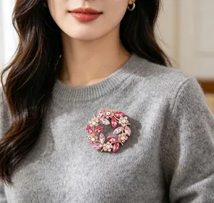 Elegant pink crystal floral wreath brooch accessory pinned on a soft grey knitted sweater detail