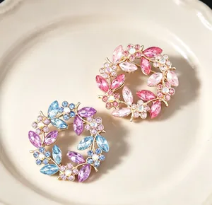Macro view of two vintage crystal wreath brooches with colorful rhinestones on a ceramic plate