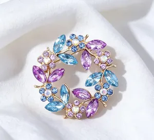 Close-up detail of vintage crystal wreath brooch featuring purple and blue rhinestones.