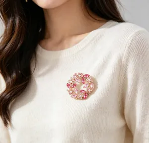 Sparkling crystal wreath brooch pinned on a cream sweater for an elegant look.
